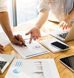 Profissionais analisando gráficos, laptop e documentos sobre mesa, representando planejamento de marketing estratégico da Birdclick em Indaiatuba.